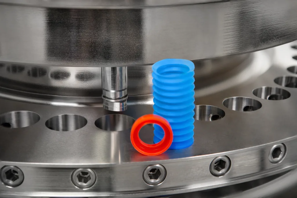 A red dust cup and blue bellow against a tablet press die table.